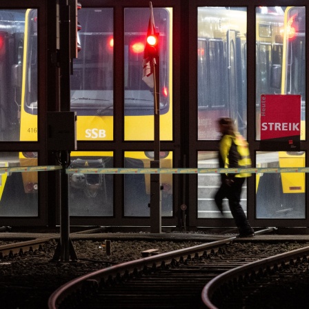 Eine Teilnehmerin eines Warnstreiks geht vor einem Stadtbahndepot der Stuttgarter Straßenbahnen AG (SSB).