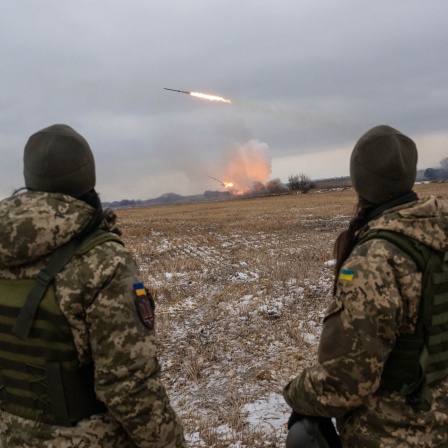 Zwei ukrainische Soldaten beobachten einen Flugkörper über einem Feld.