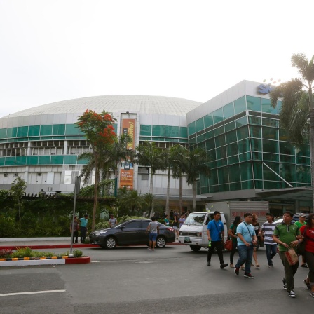 Menschen überqueren die Straße vor dem Araneta Coliseum in einem Vorort der Stadt Quezon, nordöstlich von Manila gelegen. Der "Big Dome" war vor fast 50 Jahren  der Austragungsort des epischen Schwergewichts-Boxkampfs "Thrilla in Manila" zwischen Muhammad Ali und Joe Frazier im Jahr 1975, den Ali durch einen technischen K.O. in der 15. Runde gewann.