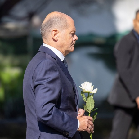 Bundeskanzler Olaf Scholz (SPD) legt eine Blume an einer Kirche in der Nähe des Tatorts in Solingen ab.