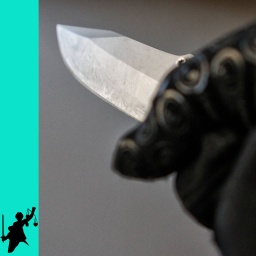 Messer wird mit einer Hand im schwarzen Handschuh gehalten