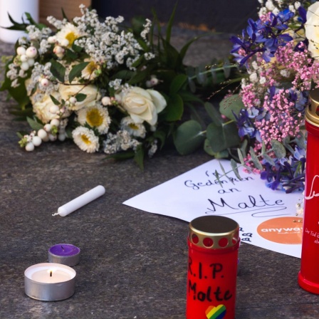 Ein Zettel "Wir gedenken Malte", daneben viele Grablichter und Blumen 