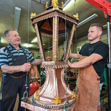 Metallbaumeister Wilfried Schwuchow steht in seiner Werkstatt zusammen mit seinem Sohn Paul, an einem Neubau einer historischen, kupfernen Straßenbeleuchtung