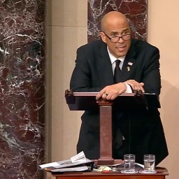 Cory Booker lehnt auf einem Rednerpult den Stift in der Hand. Die Erschöpfung nach seiner 25 Stundenrede ist ihm anzusehen.