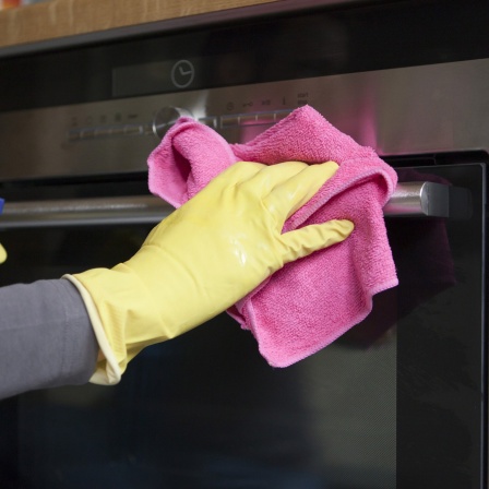 Eine Frau putzt mit einem Lappen und Reinigungsmittel den Backofen. Symbolbild Frühjahrsputz