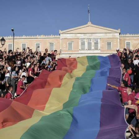 Feiernde Menschen entrollen bei der Pride Parade 2018 eine große Regenbogenflagge vor dem griechischen Parlament in Athen 