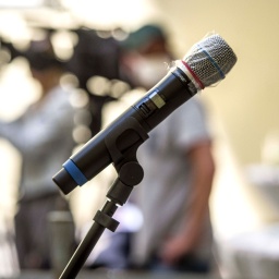 Ein Mikrofon mit Plastikschutz vor Coronaviren auf einer Pressekonferenz.