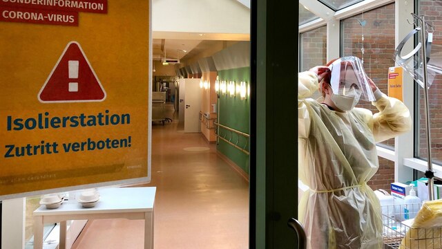 Am Eingang der COVID-19-Station im AMEOS Klinikum Ueckermünde legt eine Schwester die Schutzkleidung an. FFP3-Maske, Schutzhaube und Visier gehören genauso wie ein Schutzkittel und Handschuhe dazu.