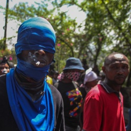 Ein Mann trägt eine blaue Maske und hat eine Zigarette im Mund. Er ist einer von Tausenden Demonstranten, die gegen den Anstieg von Bandengewalt demonstrierten.