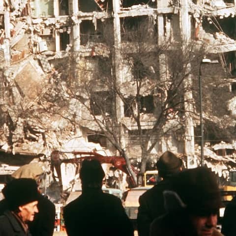 Passanten vor einem zerstörten Wohnblock in Bukarest.
