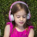 Portrait eines Mädchens auf einer Wiese, das Kopfhörer trägt