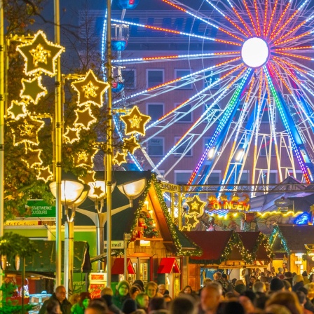 Weihnachtsmarkt in einer Innenstadt mit Beleuchtung und Riesenrad.
