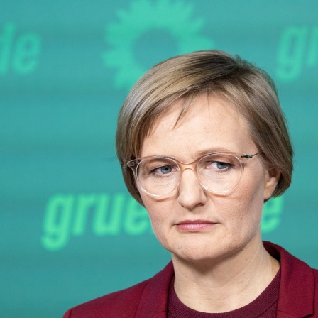 Franziska Brantner, Bundesvorsitzende von Bündnis 90/Die Grünen, spricht auf einer Pressekonferenz vor einem Hintergrund in Partei-Farben und schaut nachdenklich zur Seite.