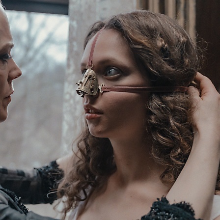 Szene aus dem Film "The Ugly Stepsister": Eine Frau setzt einer anderen einen eisernen Nasenschutz auf