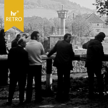  Innerdeutschen Grenze zwischen Hessen (BRD) und Thüringen (DDR). Menschen stehen auf der westdeutschen Seite, im Hintergrund ein Wachturm der DDR.