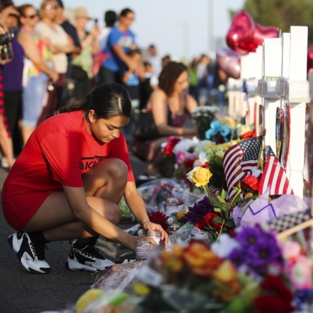Eine Frau stellt eine Kerze auf. Das Bild zeigt Trauernde am Tatort in El Paso nach einem Massaker in einem Einkaufszentrum.