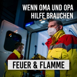 Zwei Sanitäter hinter RTW, Heck offen und Trage ragt raus