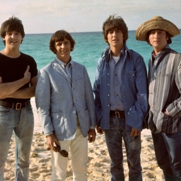Die Mitglieder der britischen Band &#034;The Beatles&#034; stehen am Strand und lachen in die Kamera.