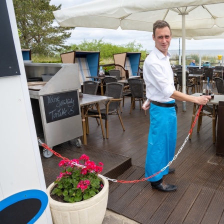 Ein Mitarbeiter öffnet den Außenbereich des Bistros.