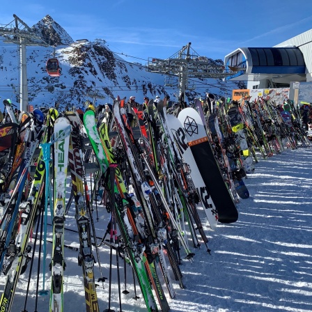 Ski und Snowboards stehen im Skigebiet am Stubaier Gletscher vor einem Lift.