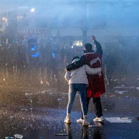 Ein Paar mit einer türkischen Flagge um den Hals wehrt sich während der Demonstration gemeinsam gegen den Einsatz von Wasserwerfern.