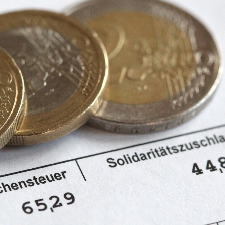 Euromünzen liegen auf einer Gehaltsabrechnung.