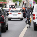 Eine Fahrradfahrerin fährt in der Dresdner Neustadt an einem auf dem Radweg parkenden Auto vorbei.