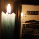 Symbolbild hohe Energiekosten: Wechselstromzaehler, davor eine brennende Kerze.