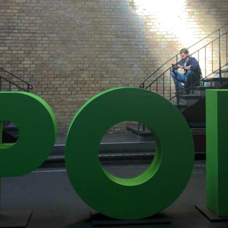 Mann sitzt auf Treppe und wird von einem Lichtschein erhellt. Im Vordergrund steht in großen grünen Buchstaben das Thema der aktuellen re:publica: “Pop”