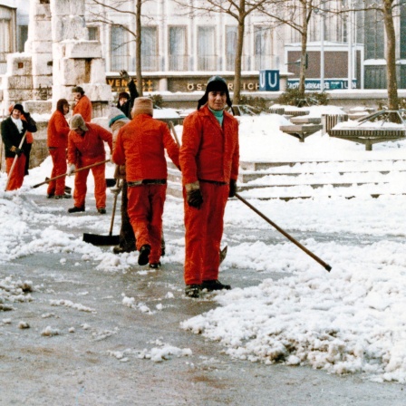 1979. Straßenreiniger kehren die Schneemassen in der Kölner Innenstadt zusammen.