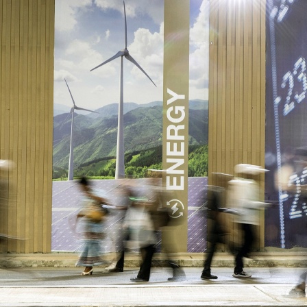 Menschen laufen während der UN-Klimakonferenz COP27 im Jahr 2022 an einem Transparent vorbei.
