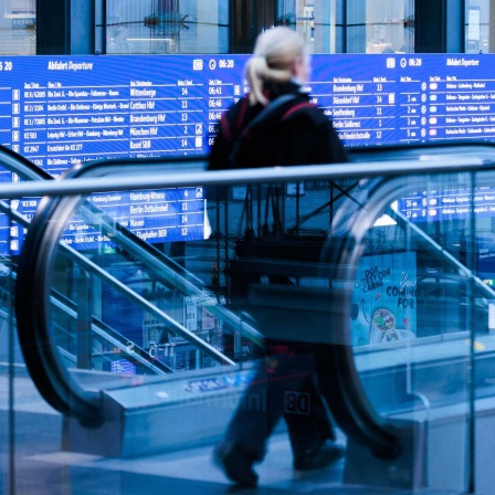 Eine Reisende geht im Berliner Hauptbahnhof an einer Anzeigetafel vorbei.