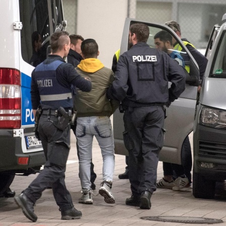 Hand- und Fußfesseln trägt ein junger Mann aus Afghanistan, den Polizisten zur Abschiebung zum Flughafen bringen. 