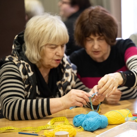 Zwei ältere Frauen häkeln im jüdischen Flüchtlingsheim Armbänder aus Wolle in den Nationalfarben der Ukraine.