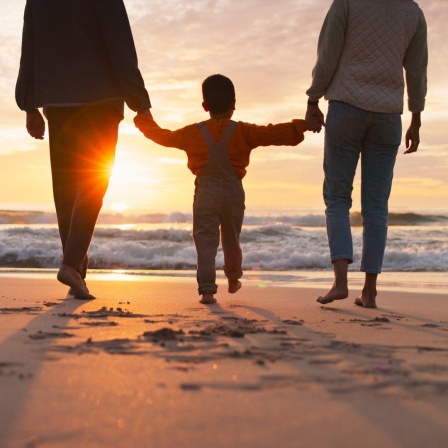 Eine Familie läuft am Strand entlang.