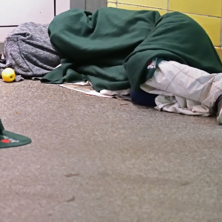 Obdachlose liegen morgens im U-Bahnhof unter einfachen Decken auf der Erde und schlafen.