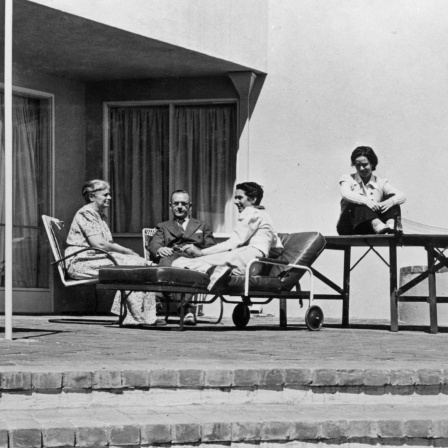 Historisches Schwarzweißfoto: Thomas Mann, seine Ehefrau Katia und die Töchter Erika und Monika sitzen auf der Terrasse seines Hauses in Pacific Palisades.