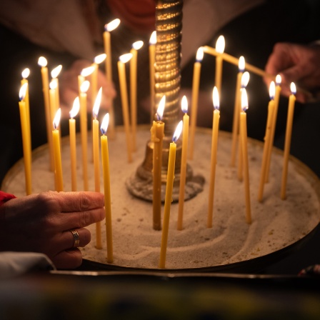 Frauen zünden 2023 während eines Gottesdienstes zum ukrainischen Weihnachtsfest Kerzen an.