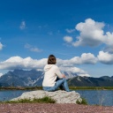 Eine Frau sitzt an einem See auf einem Stein