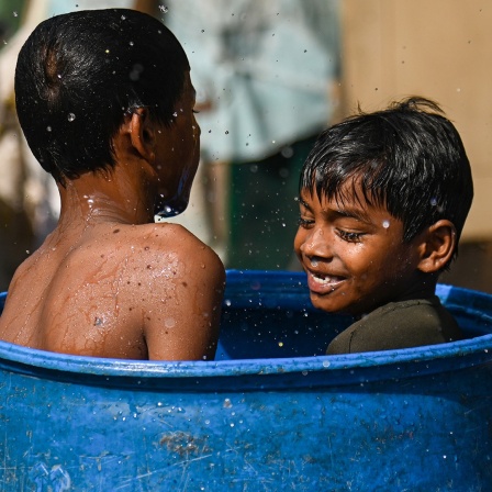Zwei kleine Jungen in Indien erfrischen sich in einer Wassertonne