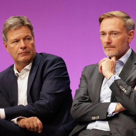 Bundeswirtschaftsminister Robert Habeck und Bundesfinanzminister Christian Lindner sitzen auf einem Podium und gucken beide nachdenklich.