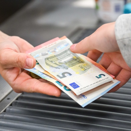 Kunde im Supermarkt gibt Geld an Kassierer