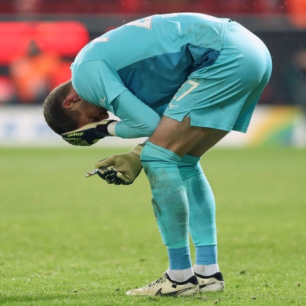 Bochum-Torhüter Patrick Drewes steht gebeugt auf dem Platz, hält sich mit einer Hand den Kopf und mit der anderen ein Feuerzeug, mit dem er in der Nachspielzeit im Bundesliga-Spiel beim 1. FC Union Berlin getroffen wurde (Bild: Imago Images/Jan Huebner)