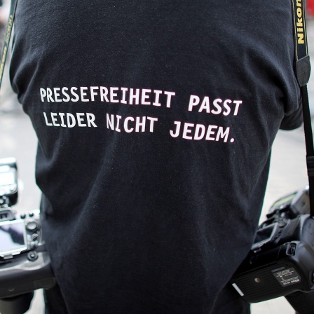 Ein Fotograf trägt ein T-Shirt mit einem Slogan für die Pressefreiheit