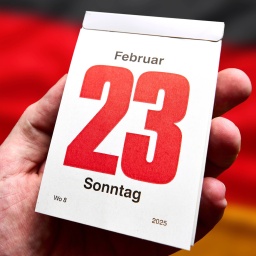 Ein Mann hält ein Kalenderblatt mit dem Datum 23. Februar 2025, Sonntag in der Hand. Im Hintergrund die Deutschlandfahne. Symbolbild für vorgezogene Bundestagswahl,  [M]