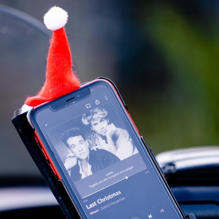 Smartphone-Display mit "Last Christmas" von Wham! und Weihnachtsmütze