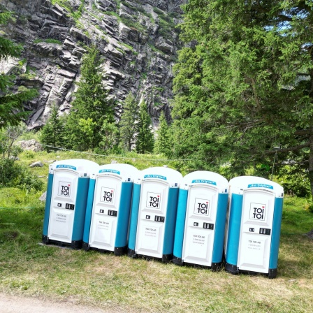 Mehrere ToiToi-Toilettenhäuschen im Gebirge: Woher kommt der Ausdruck toi, toi, toi, mit dem man jemandem Glück wünscht?