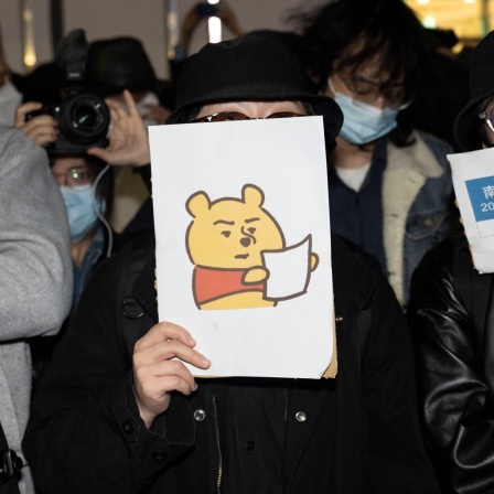 Eine Demonstrierende mit einem Winnie The Pooh Bild gegen die chinesische Obrigkeit