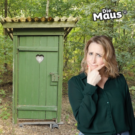 Auf dem Bild ist eine Frau mit nachdenklichem Ausdruck und die Hand am Kinn vor einem traditionellen grünen Plumpsklo mit einem Herz-Ausschnitt in einer bewaldeten Umgebung zu sehen, zusammen mit dem "Die Maus"-Logo in der oberen rechten Ecke.