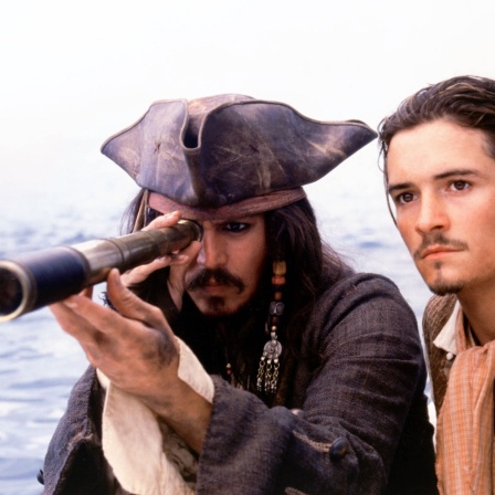 Johnny Depp schaut als Captain Jack Sparrow durch ein Fernglas. Neben ihm Orlando Bloom.